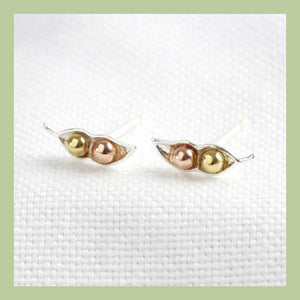 two pea pod silver stud earrings each with a gold and rose gold pea inside