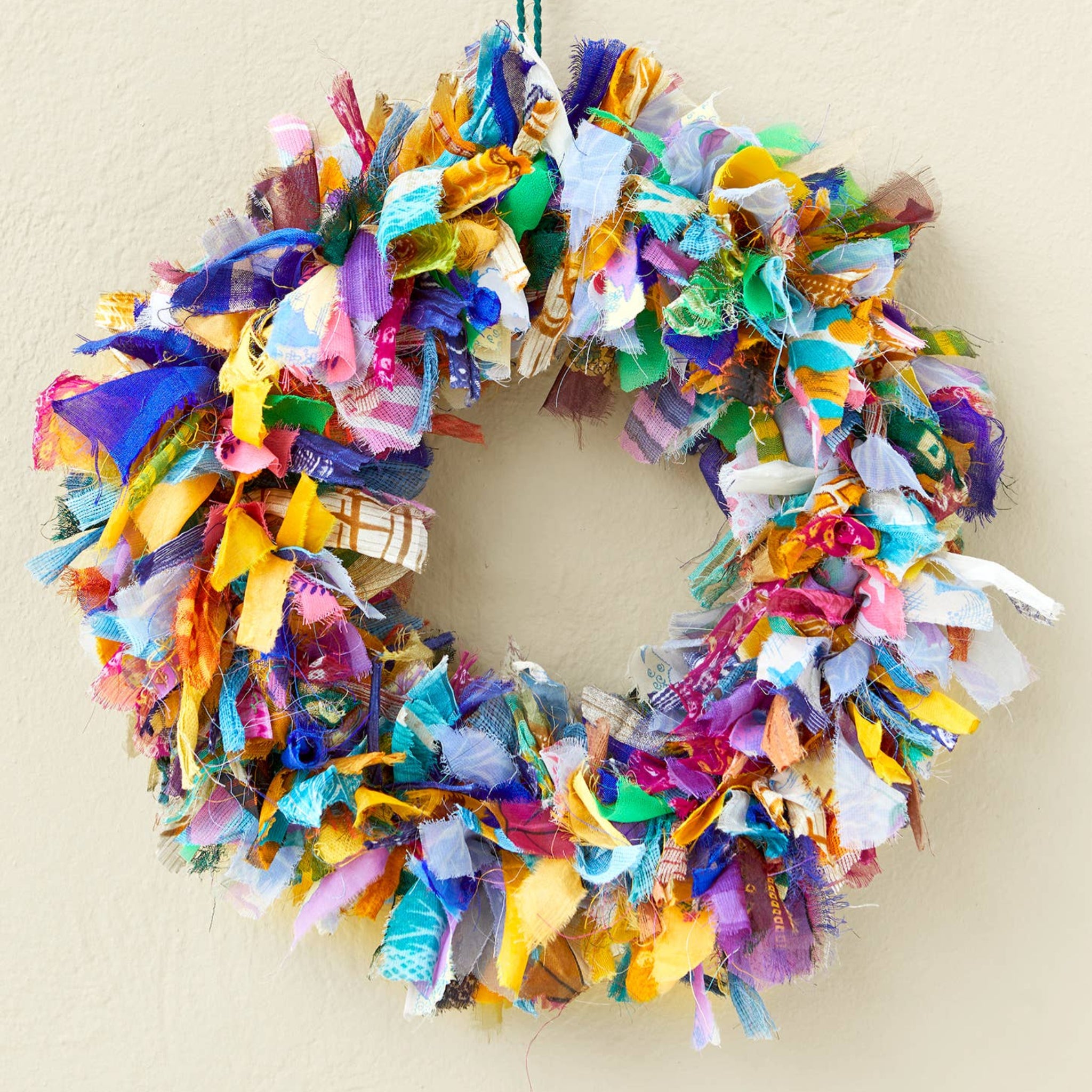 Colorful fabric wreath with a decorative hook on a beige background