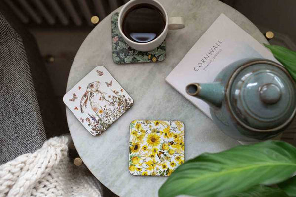Tea set with teapot, cup, and coasters on a marble table.