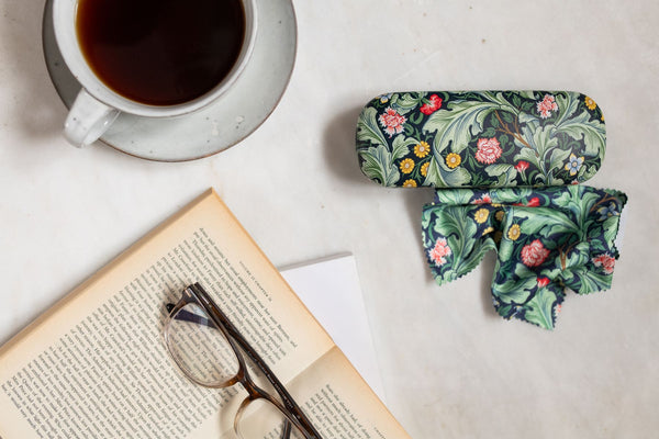 Floral eyeglass case on a table with a book and cup of coffee