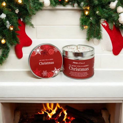 Christmas candle with red lid and festive decorations on a fireplace mantle.