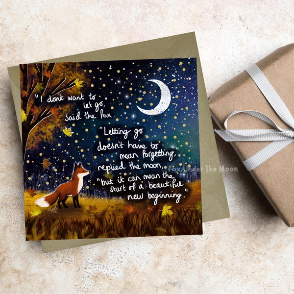 Greeting card with fox and moon illustration and inspirational quote on a textured surface with a gift box.