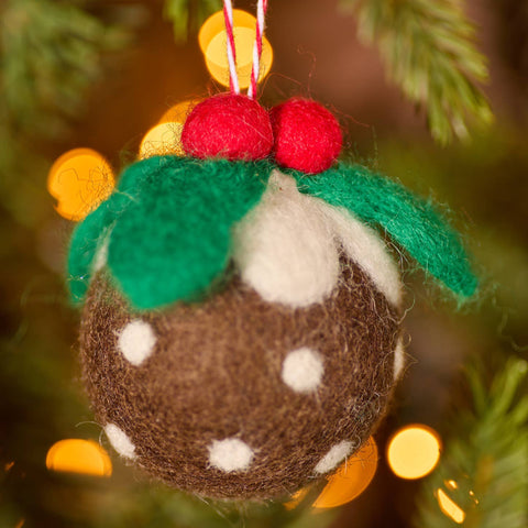 Felted Christmas pudding ornament on a tree with blurred lights in the background