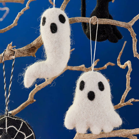 Halloween-themed decorations including white ghosts, a black cat, and a spider web on a branch against a blue background.