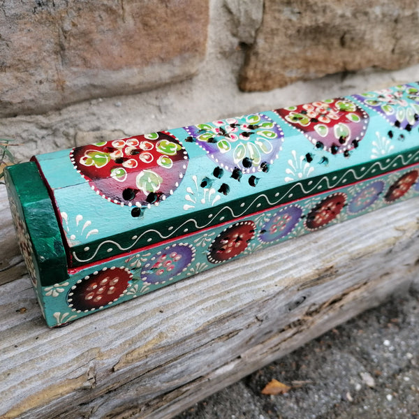 Colorful hand-painted box with floral designs on a wooden surface.