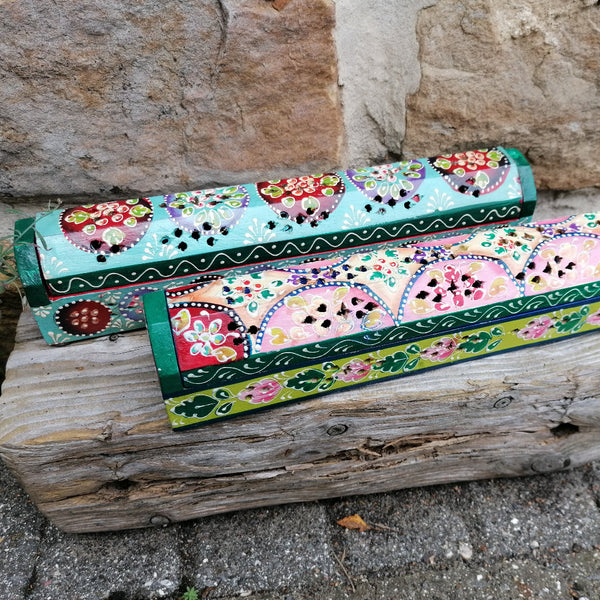 Two colorful wooden boxes with floral patterns on a stone surface.