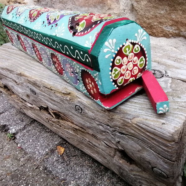 Colorful incense box with decorative patterns on a wooden log