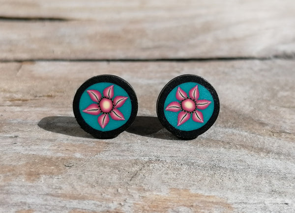 Pair of earrings with pink floral design on a wooden surface