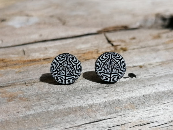Black and white patterned round earrings on a wooden surface