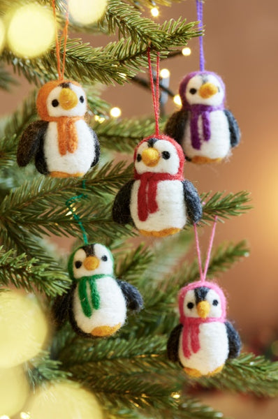 Decorative penguin ornaments with scarves on a Christmas tree.