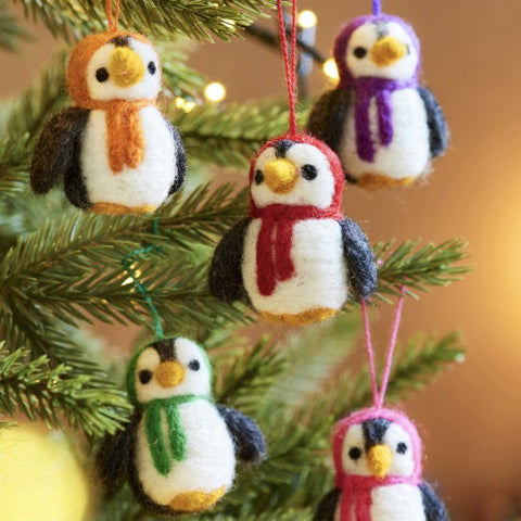 Set of felted penguin ornaments with scarves on a Christmas tree.