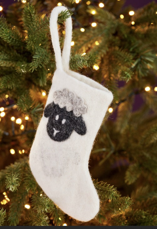 White stocking with black sheep design hanging on a Christmas tree.