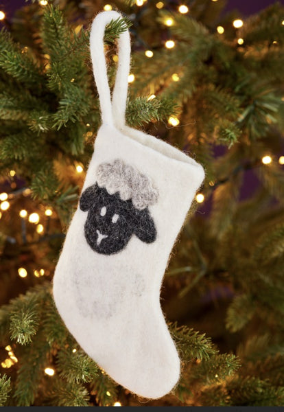 White stocking with black sheep design hanging on a Christmas tree.