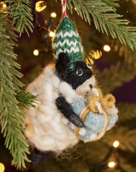 Felted animal ornament hanging on a Christmas tree with lights in the background
