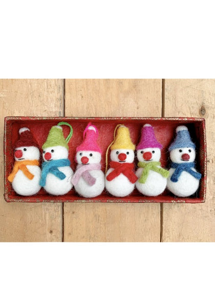 Set of six small snowmen with colorful hats and scarves in a red box on a wooden surface.
