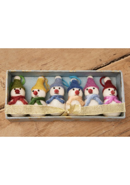 Set of six small snowman figurines with colorful hats and scarves in a box on a wooden surface.