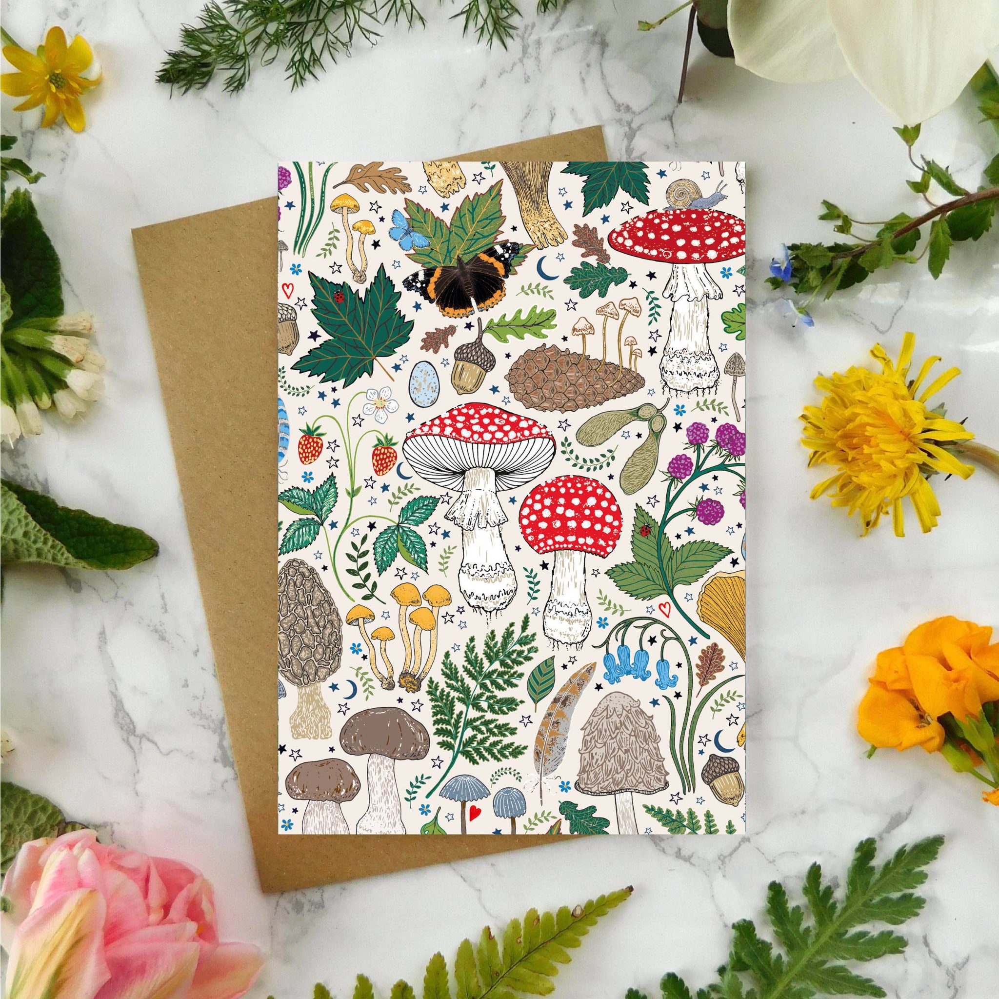 Greeting card with nature-themed design surrounded by flowers and leaves on a marble surface