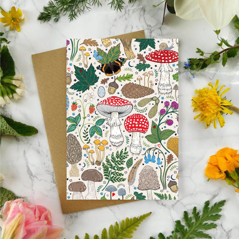 Greeting card with nature-themed design surrounded by flowers and leaves on a marble surface
