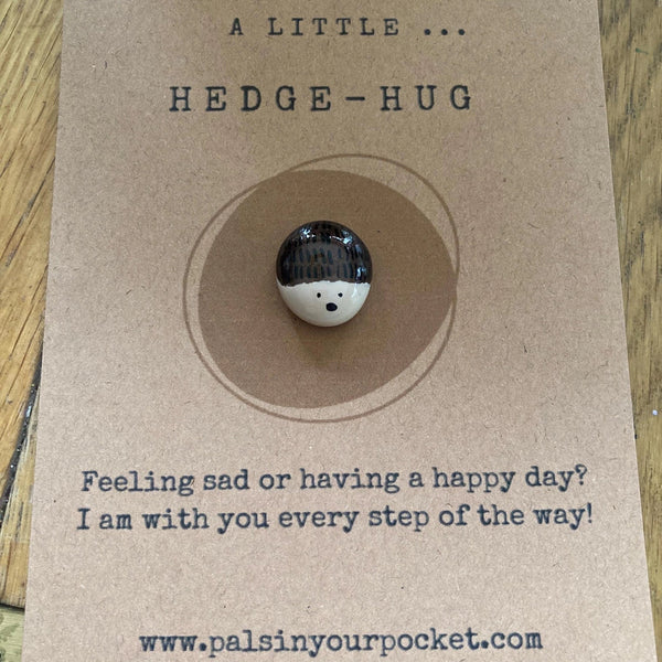 Small round hedgehog-shaped object on a brown card with text