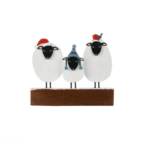 Three sheep figurines with hats on a wooden base against a white background