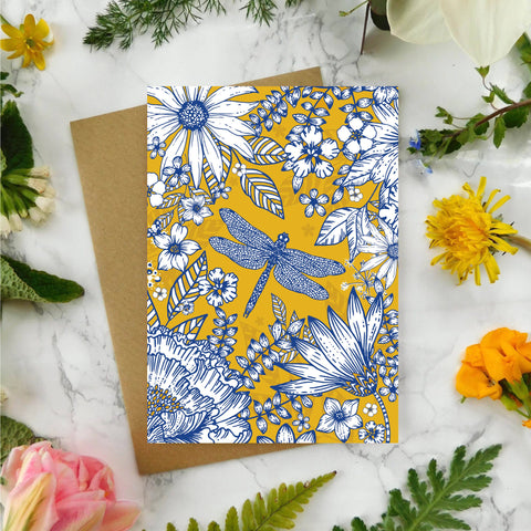 Floral and dragonfly patterned card with flowers and leaves on a marble surface