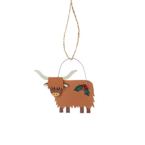 Decorative highland cow ornament with holly on a white background