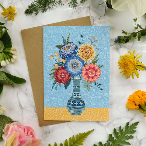 Greeting card with floral design on a marble surface surrounded by flowers and leaves