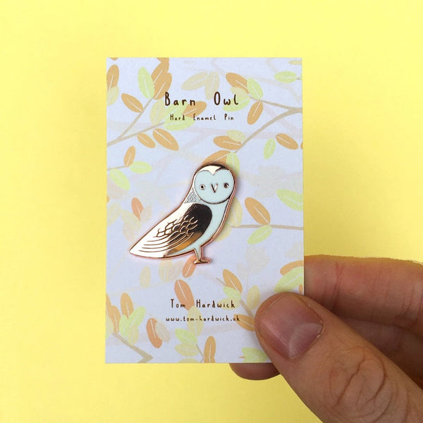 Barn owl pin held over its packaging with a yellow background
