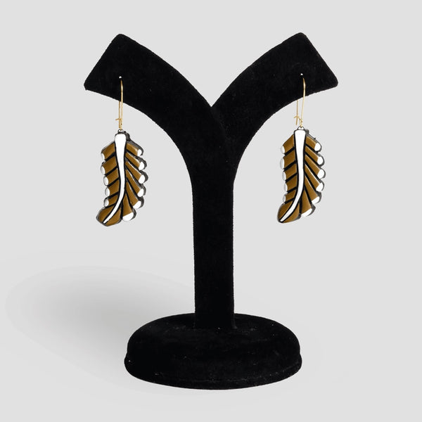 Pair of feather-shaped earrings on a black velvet stand against a light gray background
