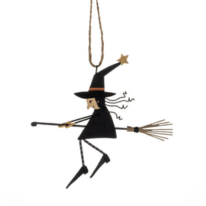 Decorative witch figure on a broomstick hanging from a string against a white background