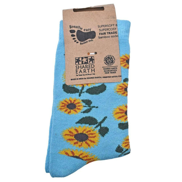 Blue socks with sunflower pattern and Shared Earth packaging on a white background