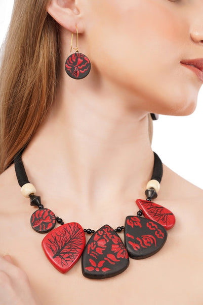 Necklace and earrings with red and black designs on a model against a neutral background