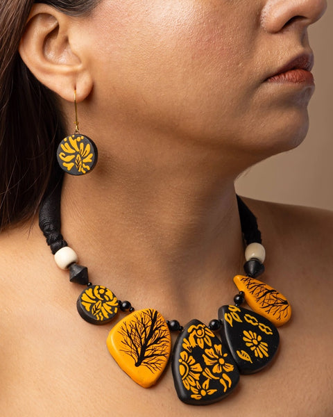 Close-up of a person wearing a necklace with black and yellow floral patterns on a neutral background