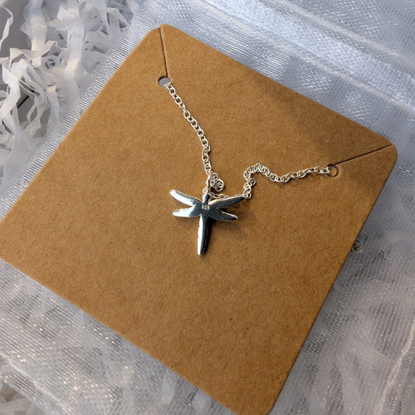 Silver necklace with a star pendant on a brown card against a white background