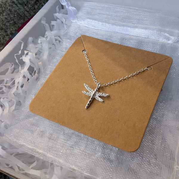 Silver necklace with a starfish pendant on a brown card inside a clear box.