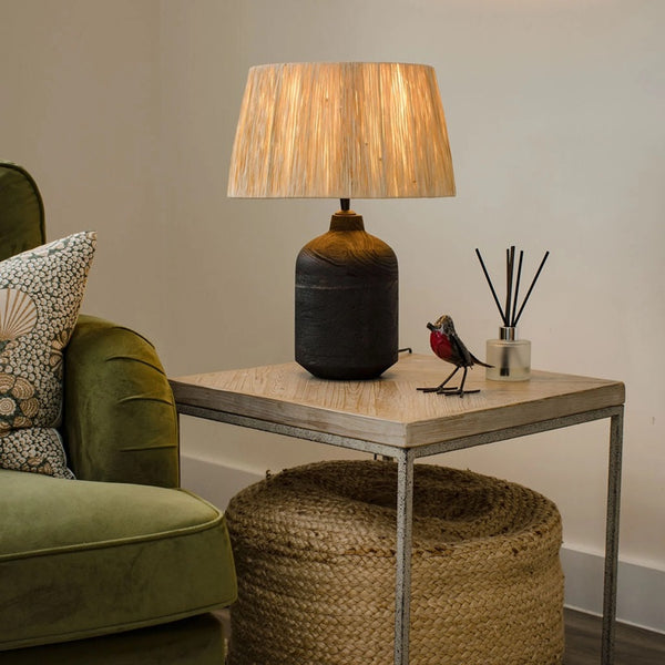 Living room with a lamp on a table, green sofa, and decorative items.