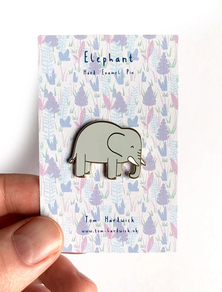 Elephant enamel pin on a patterned card held by a hand