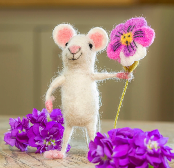 Stuffed mouse toy holding a pink flower with a blurred background