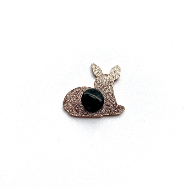 A small metallic bunny-shaped accessory with a textured rose gold finish and a glossy black oval center, photographed on a plain white background.