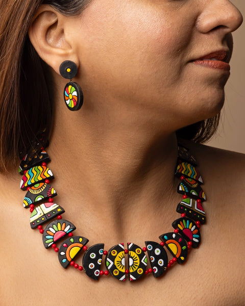 Close-up of a person wearing a colorful necklace and earrings with a neutral background
