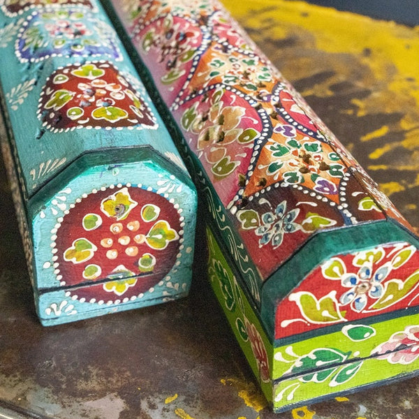 Two colorful, hand-painted wooden boxes on a dark surface.