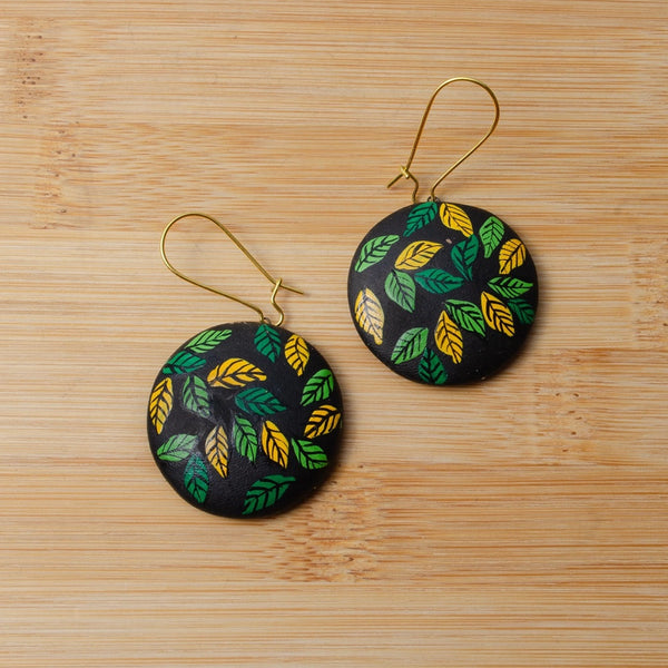 Pair of earrings with leaf pattern on a wooden surface