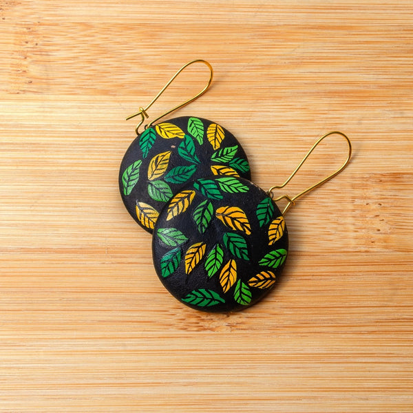 Pair of earrings with leaf pattern on a wooden surface