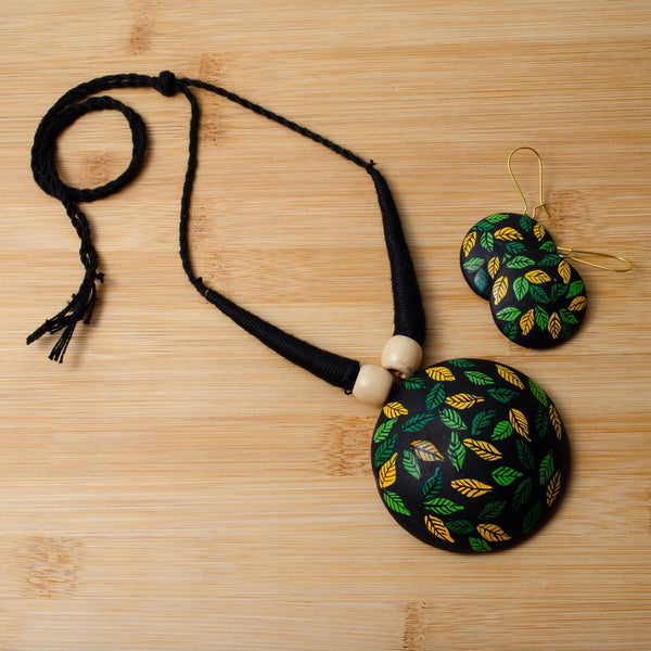 Necklace and earrings with leaf pattern on a wooden surface