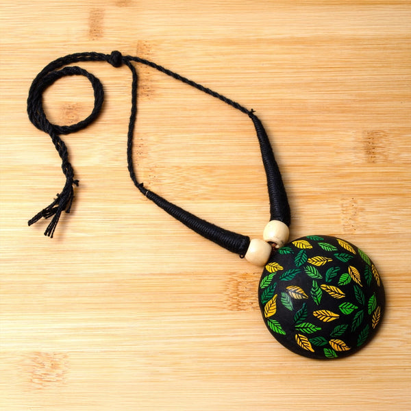 Necklace with a round pendant featuring leaf patterns on a wooden surface