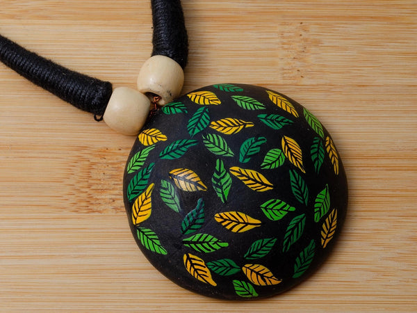 Black pendant with leaf pattern on a wooden surface