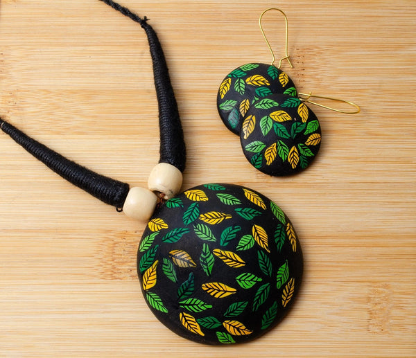 Necklace and earrings with leaf pattern on a wooden surface
