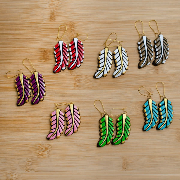 Set of colorful feather-shaped earrings on a wooden surface