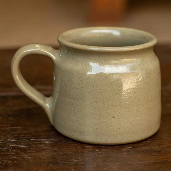 Beige ceramic mug on a wooden surface with a blurred background