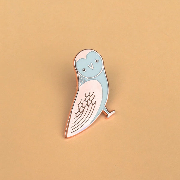 Enamel pin of a stylized owl on a beige background